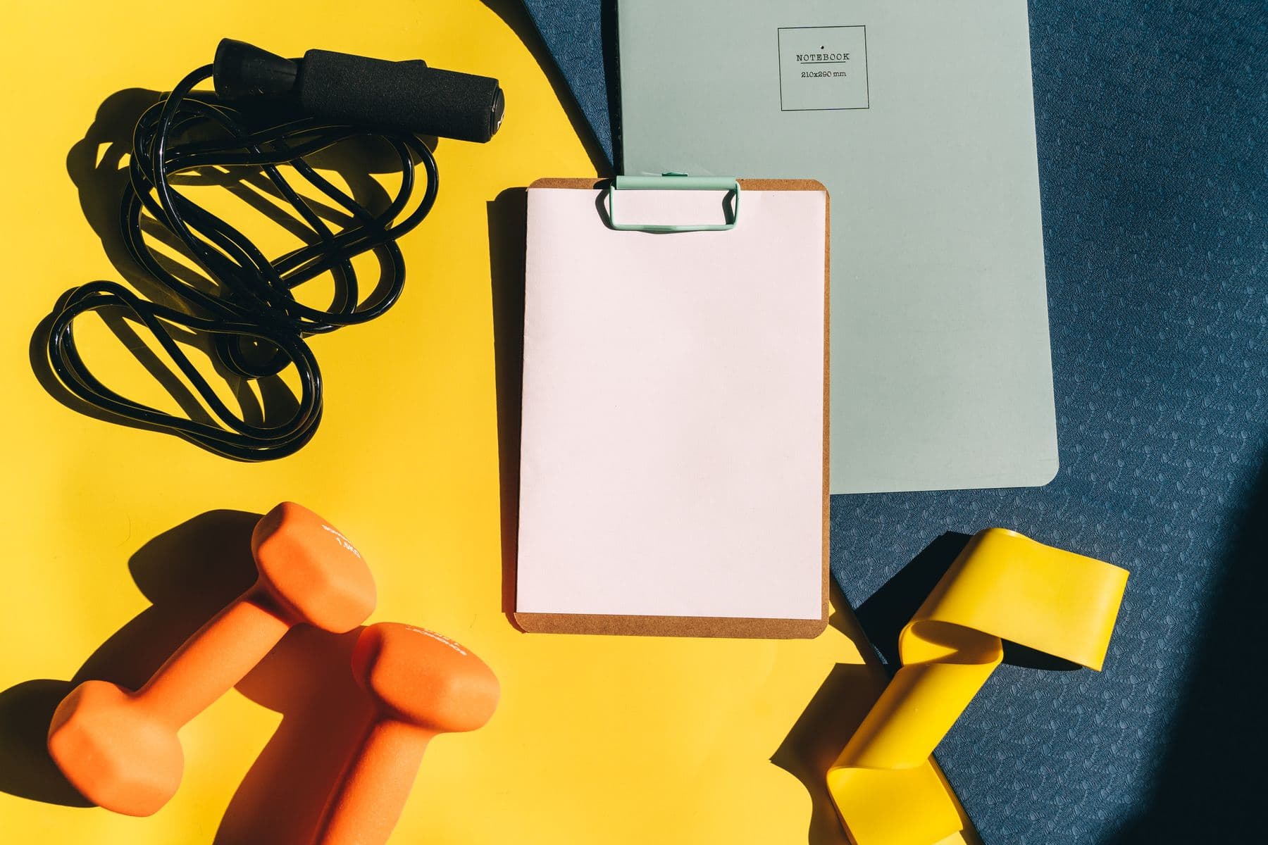 Compact home training equipment with dumbbells, band, mat, and clipboard