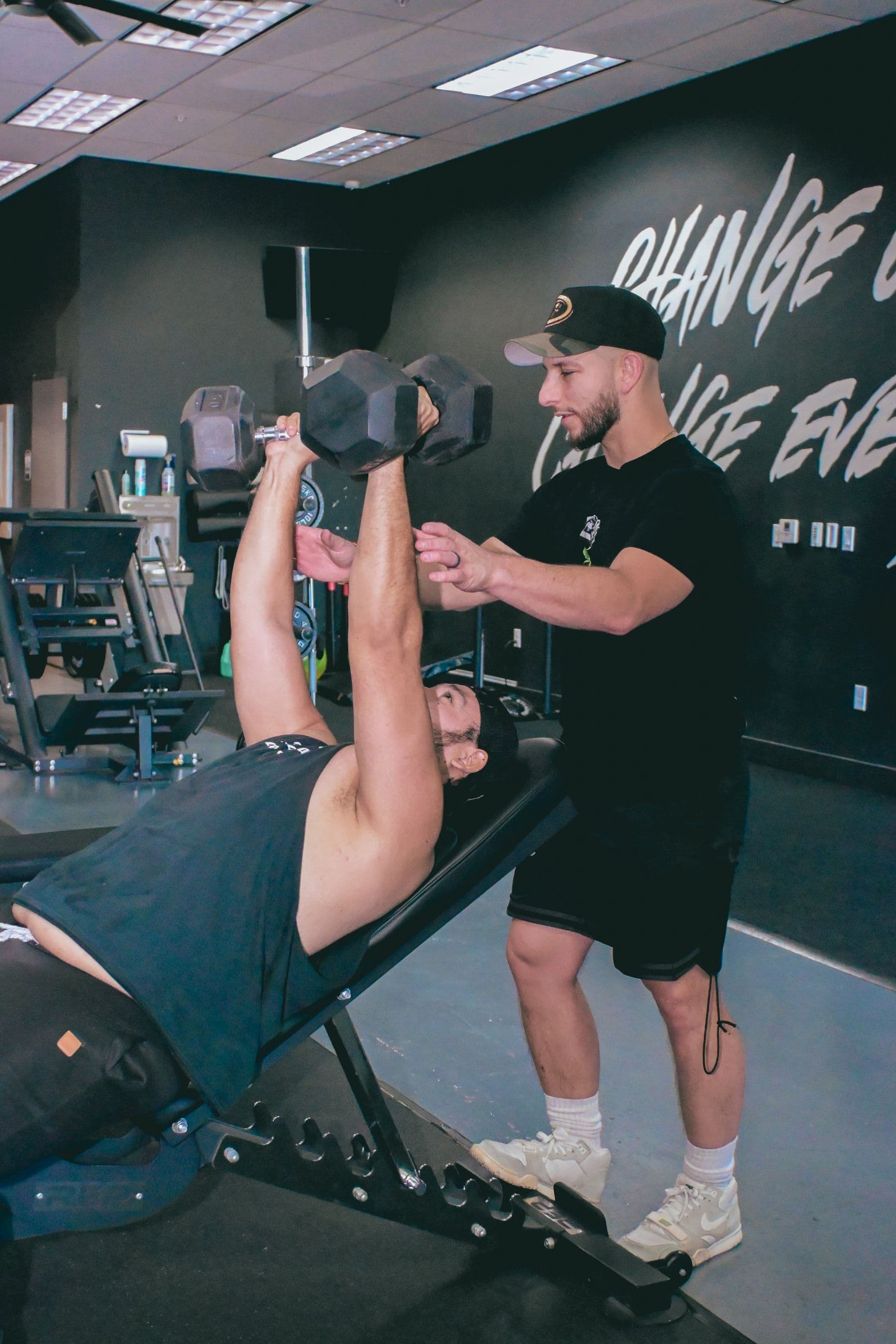 Trainer spotting a dumbbell strength exercise