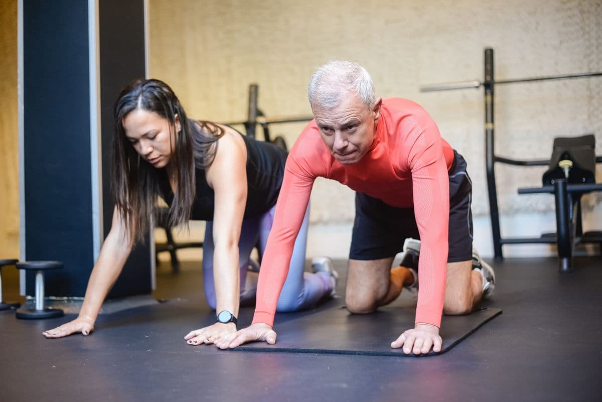 Personal trainer coaching an older adult through a strength exercise