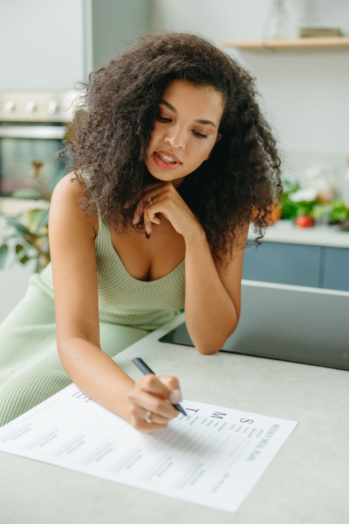 Woman writing a weekly meal plan beside fresh produce