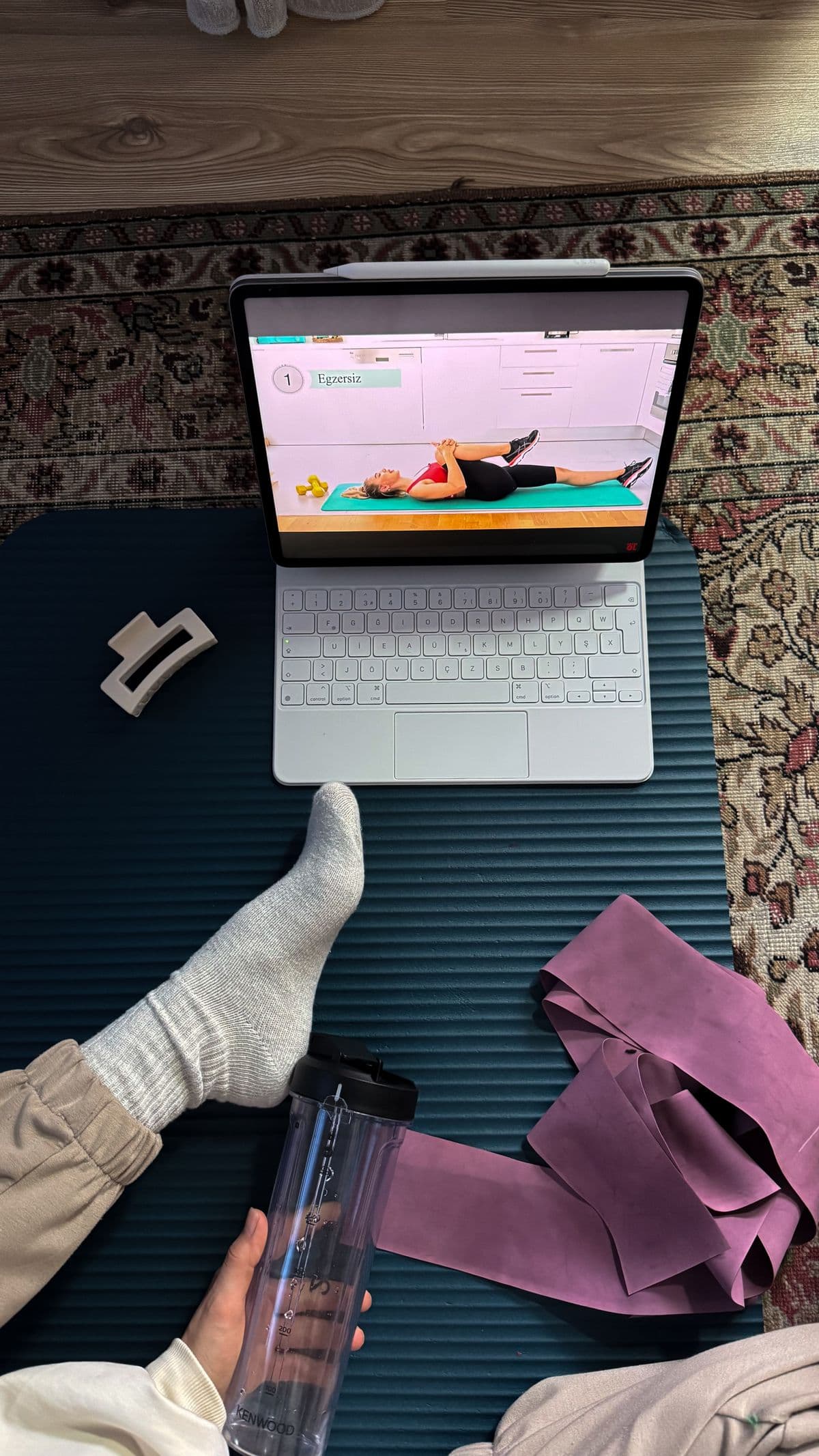 Laptop, resistance bands, mat, and water set up for an online workout