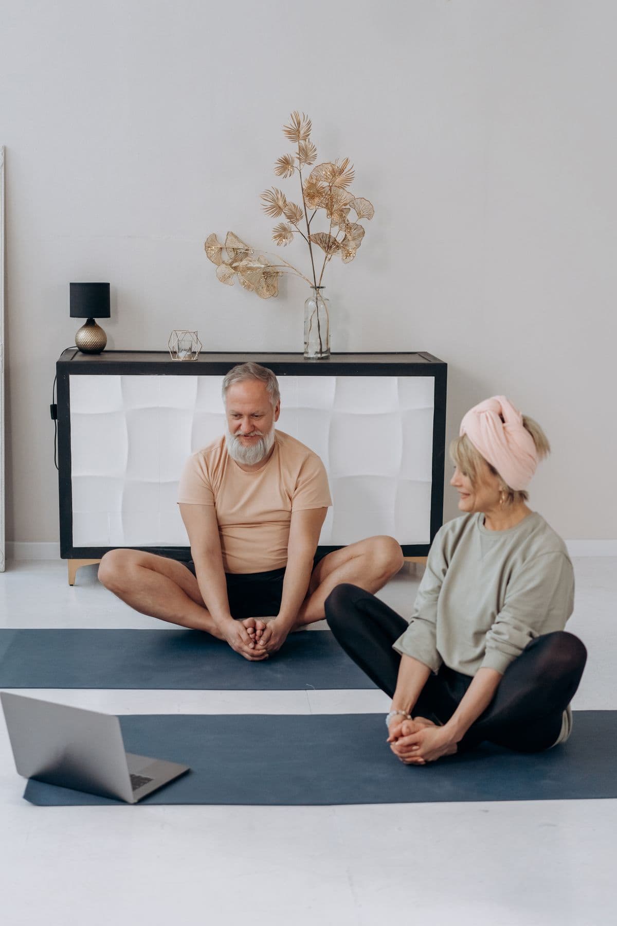 Older partners exercising together at home with individual mats