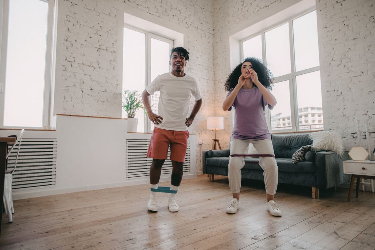 Two partners exercising with resistance bands in their living room