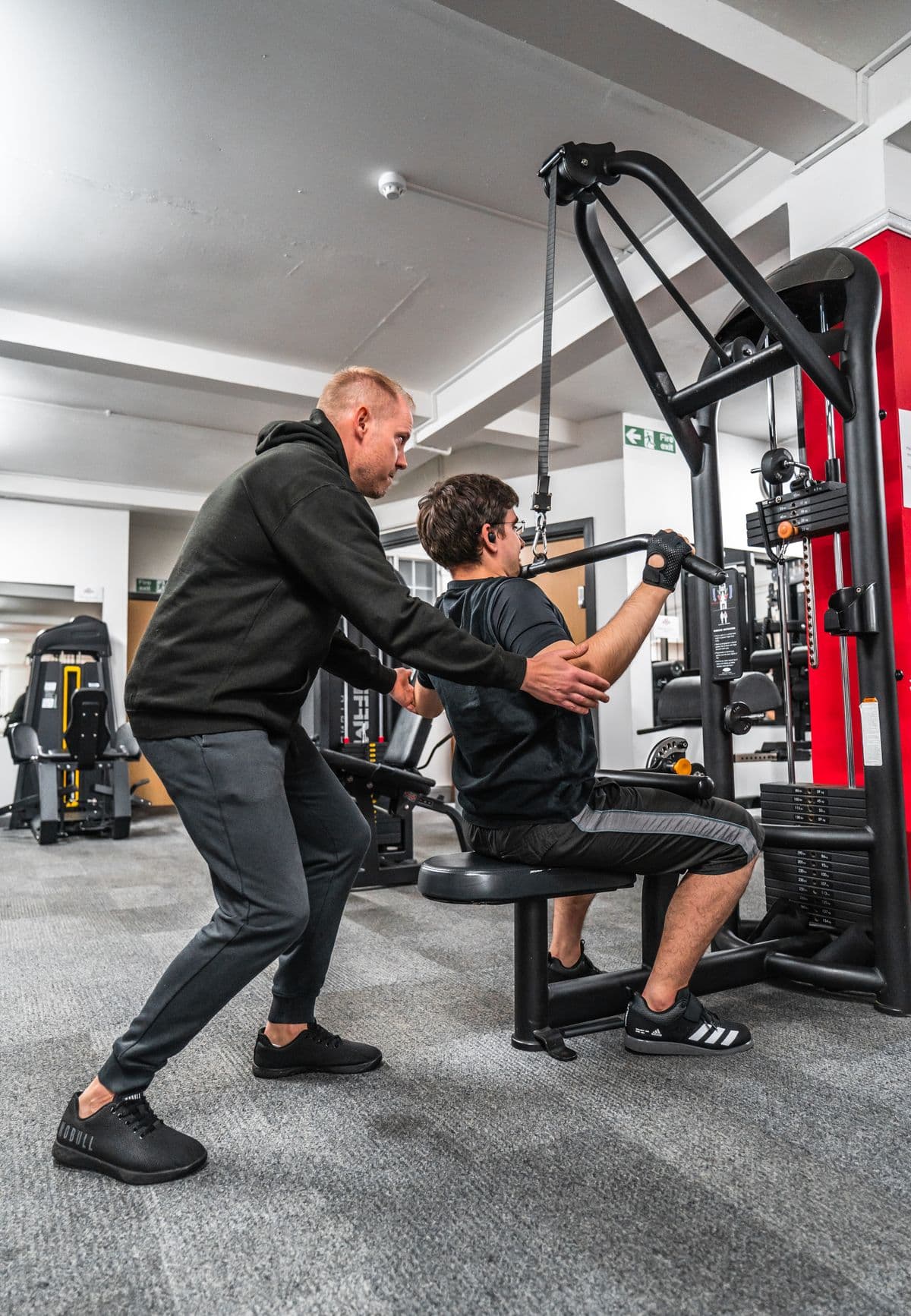Personal trainer guiding a client on a strength machine