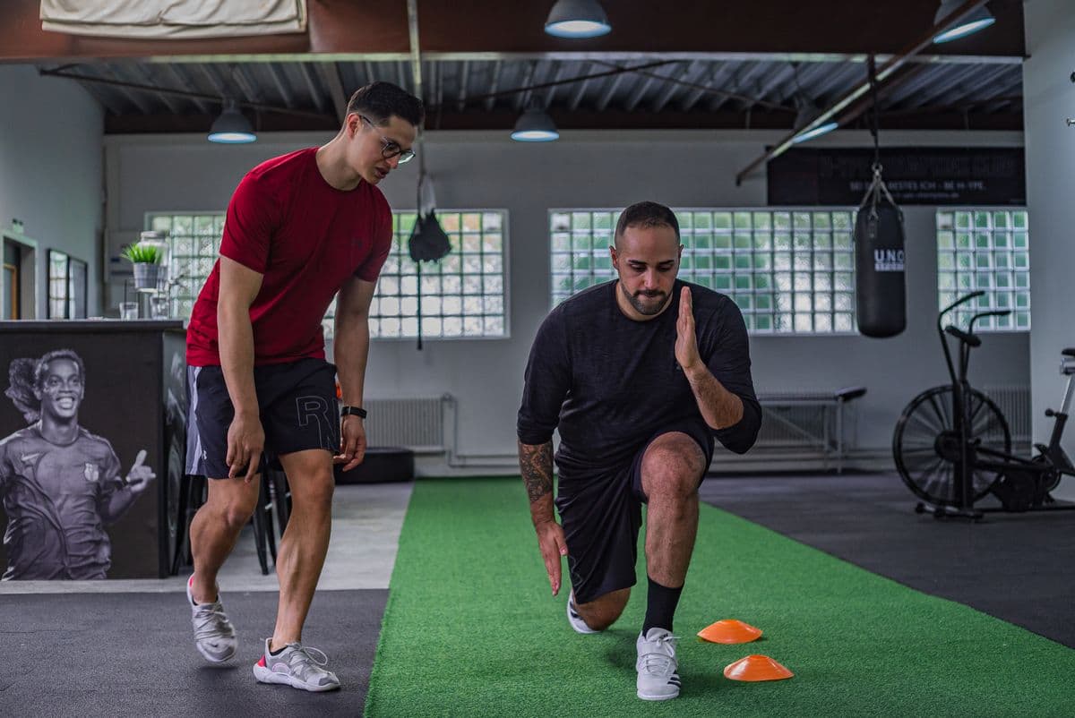 Trainer coaching a client through a strength exercise