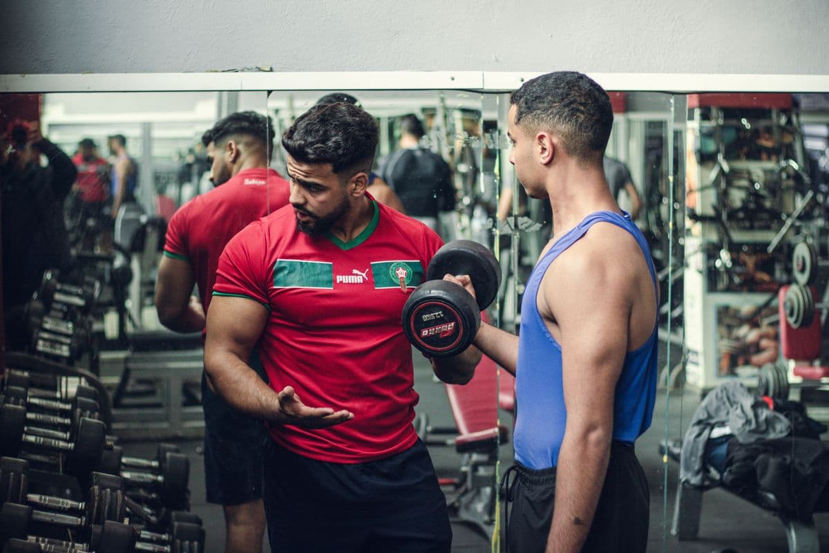 Fitness coach supporting a client during dumbbell training