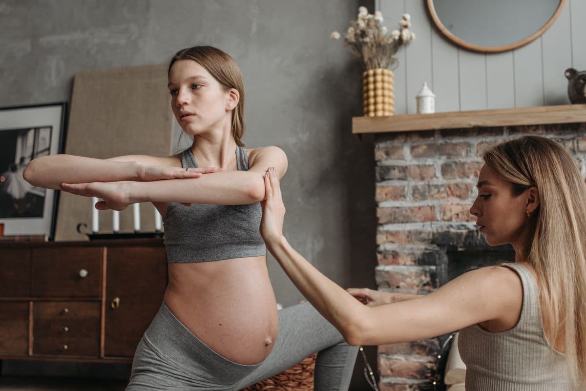 Trainer guiding a pregnant client through a supported home exercise