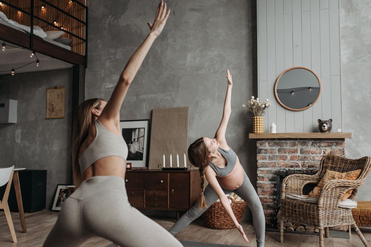 Personal trainer supporting a pregnant client during a gentle workout
