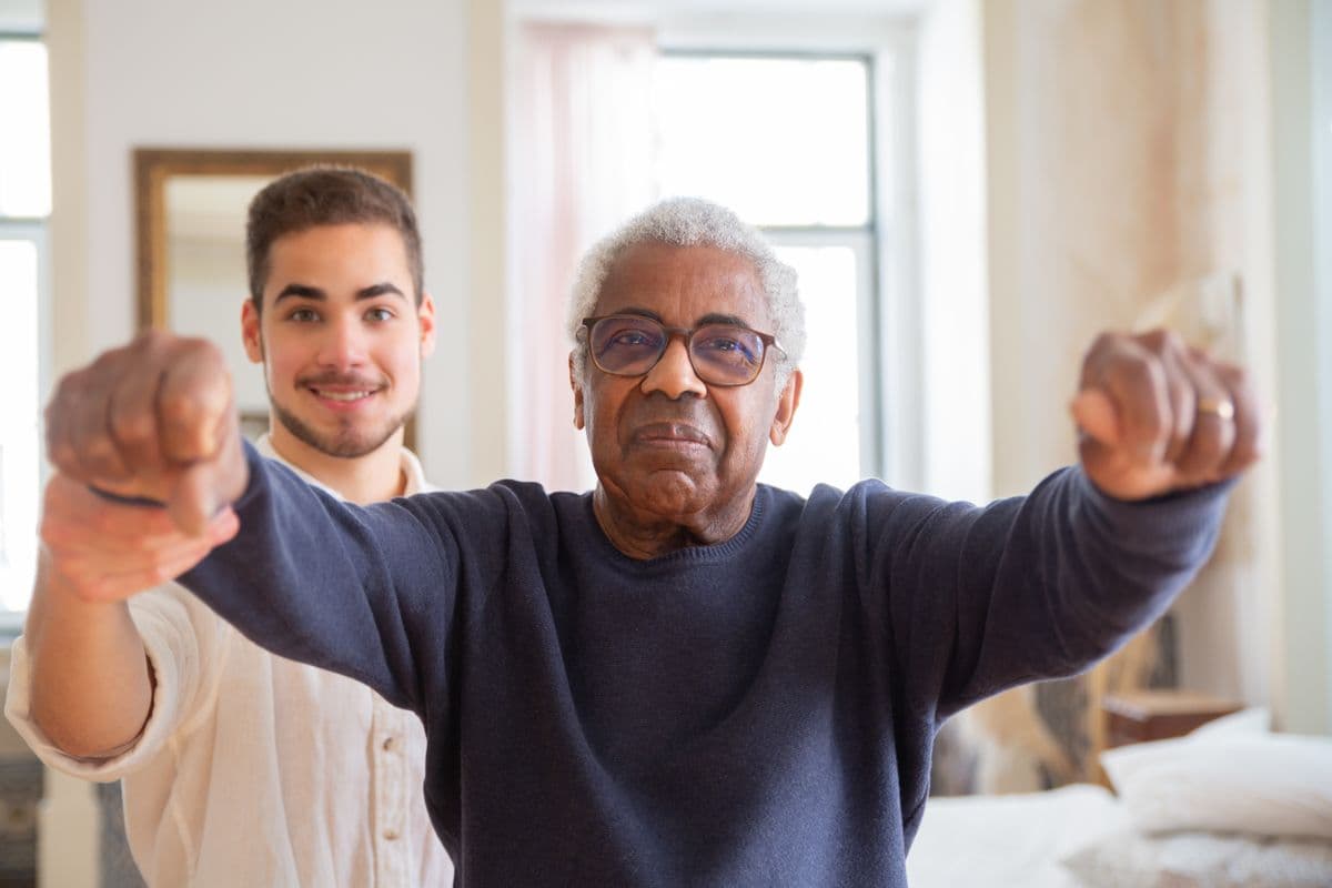 Trainer supporting an older adult during a balance exercise